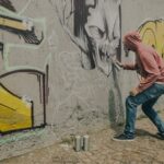 Heranwachsender sprüht Graffiti an Wand