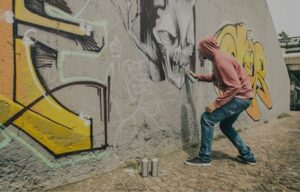 Jugendlicher macht Graffiti an Wand